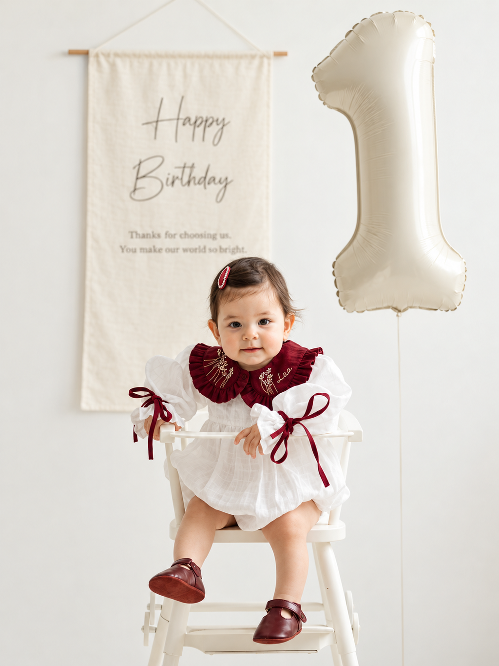 Close-up of personalized embroidered white and burgundy baby romper