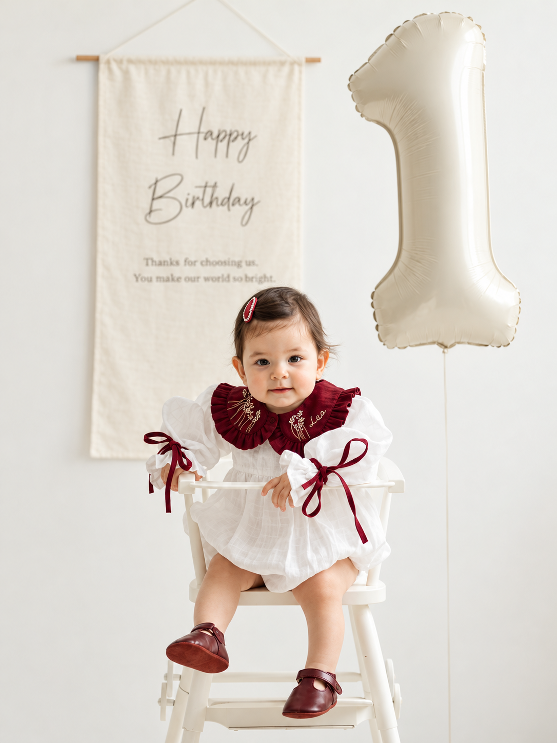 Close-up of personalized embroidered white and burgundy baby romper