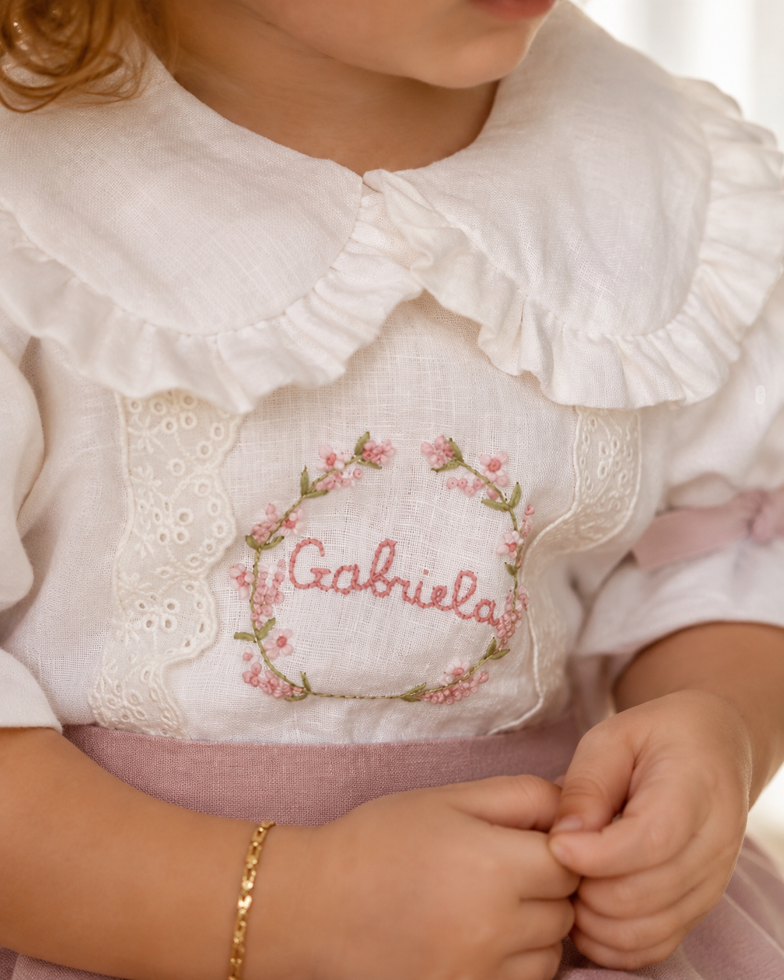 Close-up of floral name embroidery on white and dusty pink girls dress
