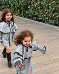 Girls wearing grey checkered dresses with black-trimmed cape collars