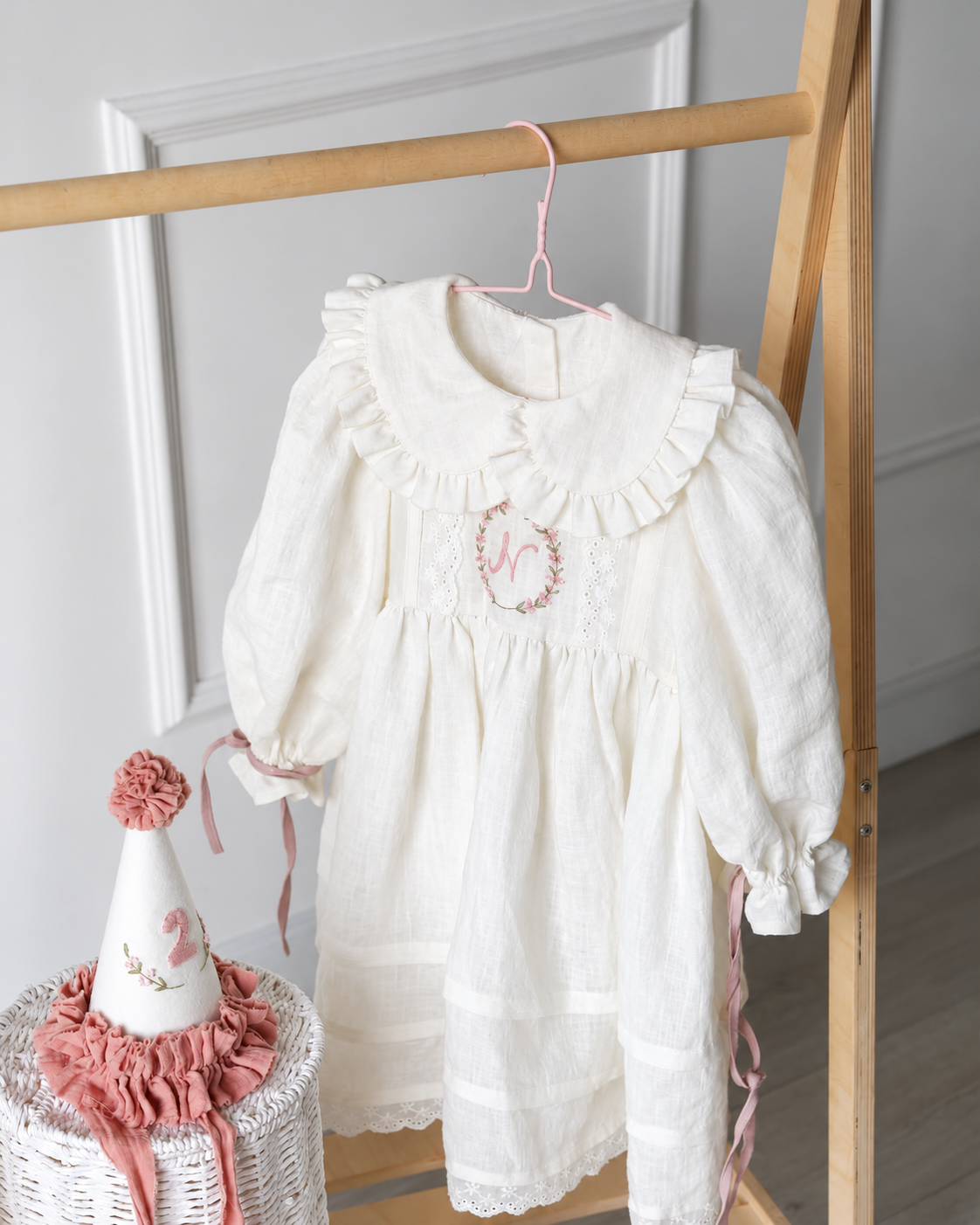 Ivory floral embroidered birthday dress on hanger beside party hat
